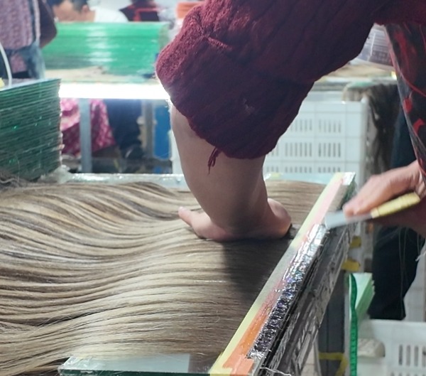 a person applying glue on a Genius Weft hair extension