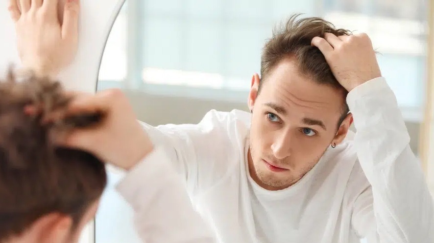 a man looking in the mirror, worring about whether his hairline is receding