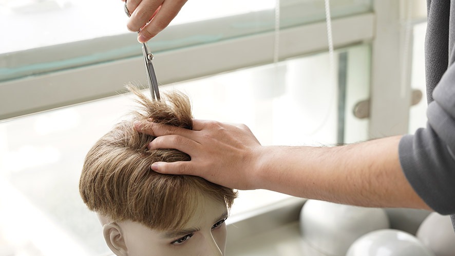 Bono Hair Stylist trimming a pre-cut hair system to create a boy bangs hairstyle