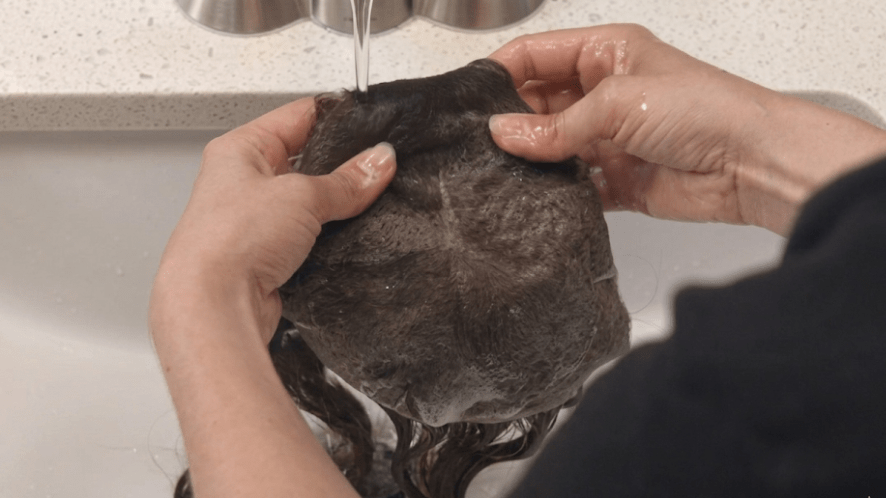 Washing a men's toupee under the tap water