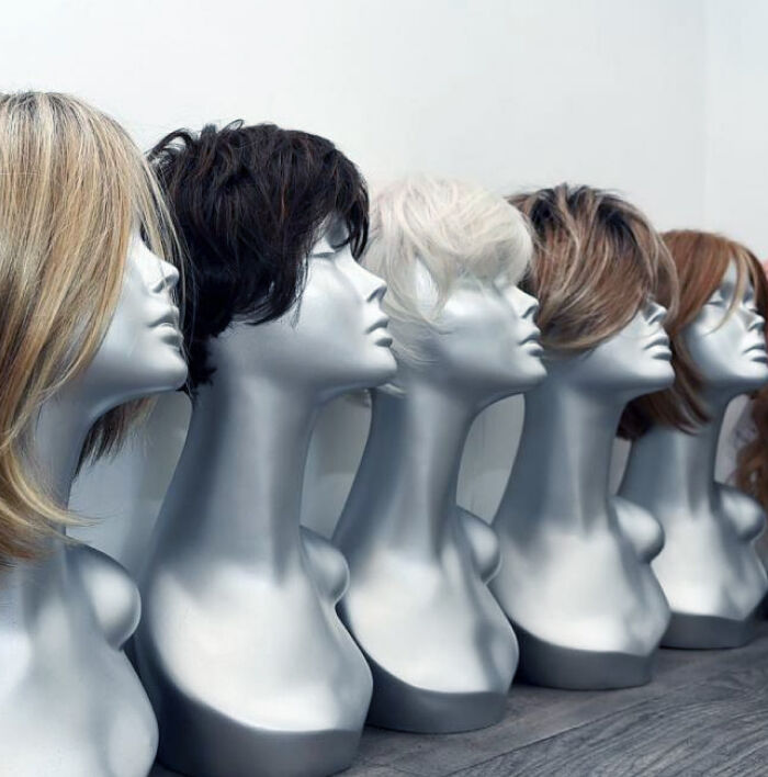 Wholesale human hair wig display: A row of mannequin heads showcasing diverse wig styles, colors, and textures, side profile
